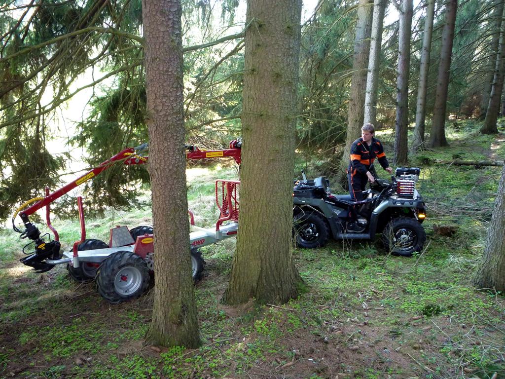 Čtyřkolka s přívěsem Kranman a hydraulickou rukou při práci v lese