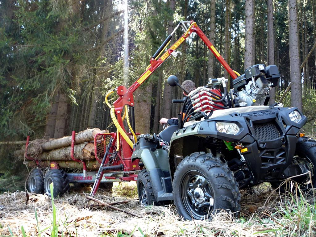 Čtyřkolka s vyvážecím přívěsem Kranman a hydraulickou rukou při nakládání dřeva