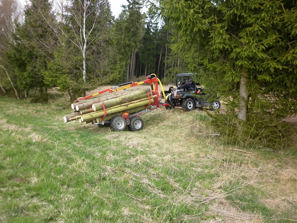 Čtyřkolka s vyvážecím přívěsem Kranman naloženým dřevem na lesní louce