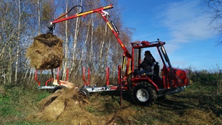 Hydraulická ruka přívěsu Kranman za traktorem zvedá drapákem kus zeminy