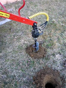 Zemní vrták na hydraulické ruce Kranman při vrtání do země